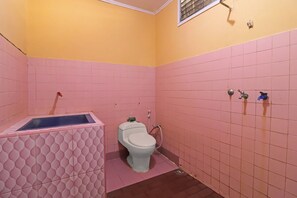 A bathroom with pink tiled walls, a white toilet, a small window, and a shower area. - Ardilia Kost Syariah (Jambi)