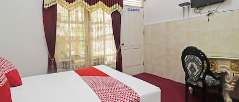 Habitación de hotel con cama, escritorio, silla, televisión y un reloj en la pared.
