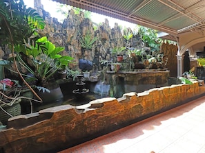 Un jardin de rocaille agrémenté d’un élément aquatique, de plantes en pot et d’un sentier en pierre.
