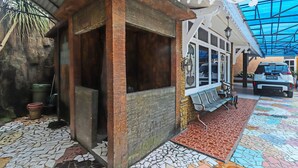 Een gebouw met een rustieke houten constructie, een betegelde vloer en een auto die ervoor geparkeerd staat.