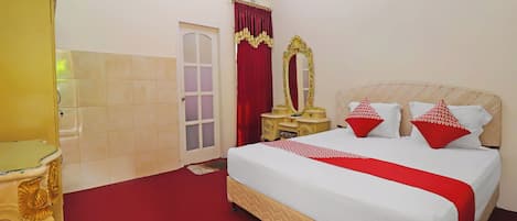 Una habitación de hotel con una cama, un tocador con espejo, una puerta y un equipo de aire acondicionado.