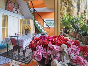 A dining area with a table and chairs, a staircase, and a variety of potted plants. - Ardilia Kost Syariah (Jambi)