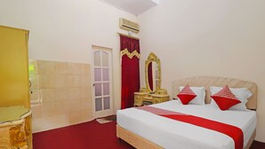 Een hotelkamer met een bed, een kaptafel met spiegel en een deur.