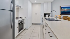Een moderne keuken met witte kasten, een roestvrijstalen koelkast, een gasfornuis en een spoelbak.