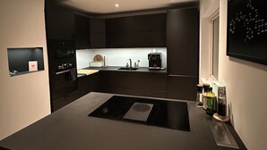 Uma cozinha moderna com armários escuros, uma ilha central e uma janela.