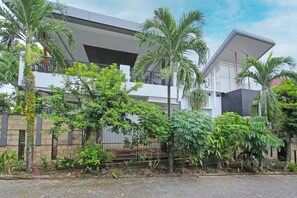 A modern two-story building with a balcony, surrounded by lush greenery and a paved walkway. - Oyo 91665 D'prof Exclusive Guesthouse (Semarang)