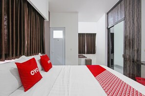 A hotel room with a large bed, two red pillows with "OYO" branding, a red and white patterned runner, a small stool, and a sliding glass door leading to a balcony. - Oyo 91665 D'prof Exclusive Guesthouse (Semarang)