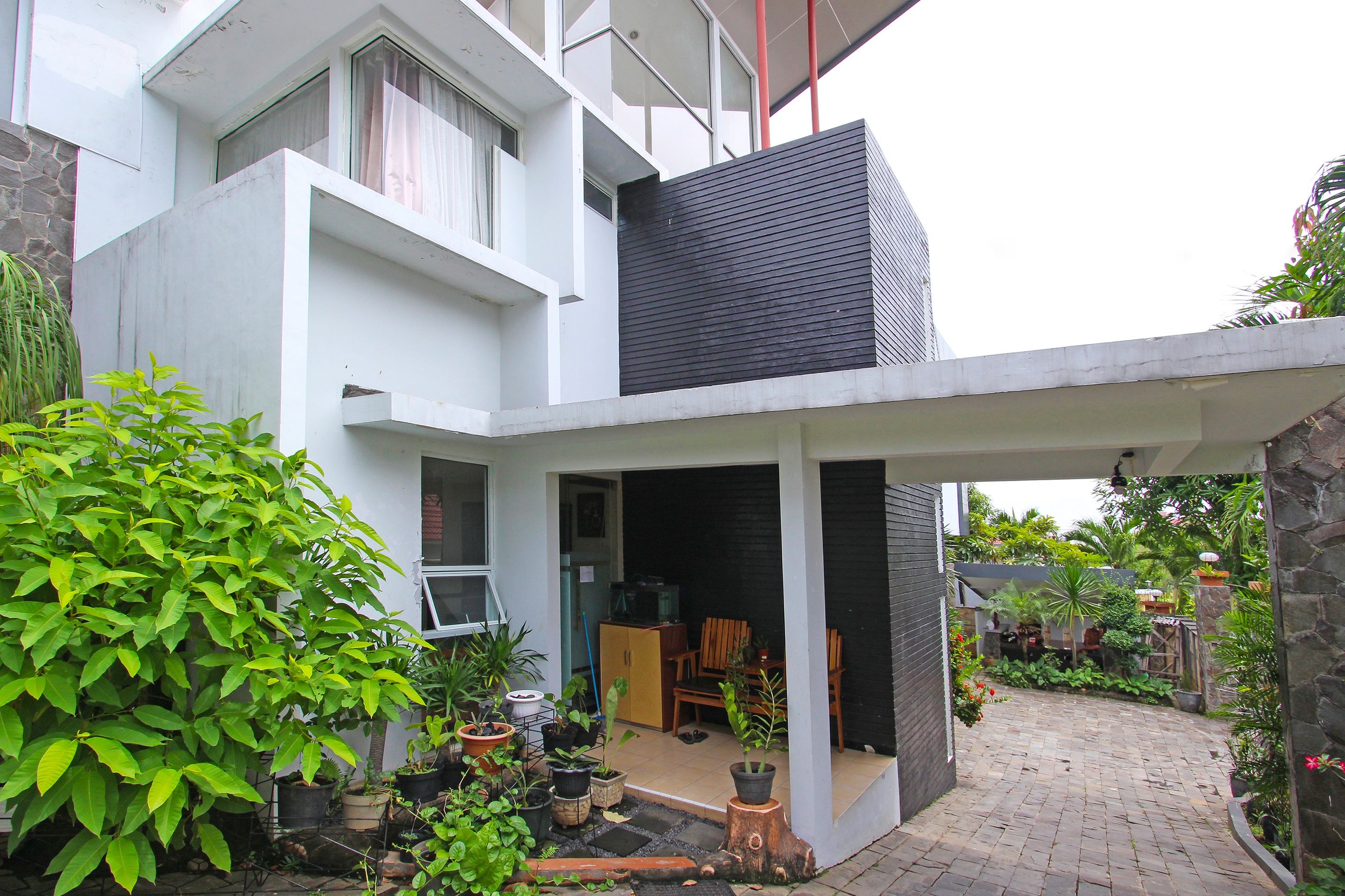 A modern house with a covered patio, potted plants, and a stone wall.