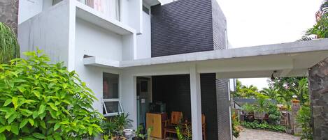 A modern house with a covered patio, potted plants, and a stone wall.