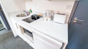 Een kleine keuken met een spoelbak, fornuis, broodrooster en koffiezetapparaat.