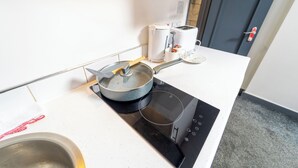 A modern kitchen with a built-in induction cooktop, a pot on the cooktop, a coffee maker, and a toaster.