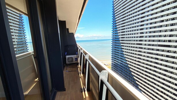 Un pasillo con vistas al mar y un edificio con ventanas horizontales.