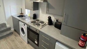 Ett kompakt kök med tvättmaskin, spishäll och brödrost.