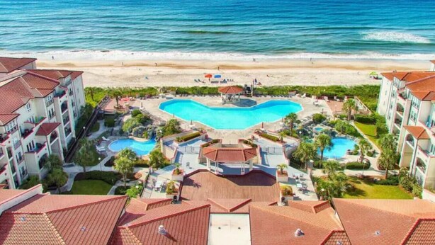 Ein Resort mit einem zentralen Schwimmbad, mehreren kleineren Pools und Blick auf den Strand.