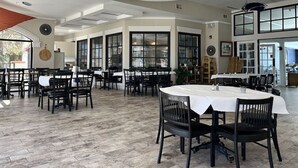 Ein geräumiges Restaurant mit hohen Decken, großen Fenstern und modernem Interieur.