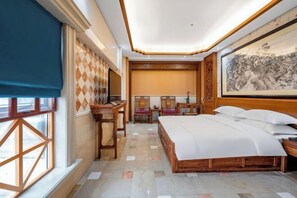 Una habitación de hotel con una cama grande, un escritorio, una silla y una ventana con vistas.