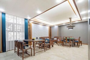 Una sala de estar moderna con comedor, que incluye muebles de madera, un ventanal grande con cortinas azules y un panel decorativo en la pared.