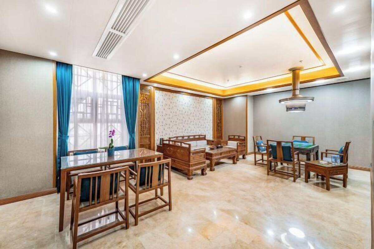 A spacious room with a dining table and chairs, a sofa set, and a decorative wall panel.