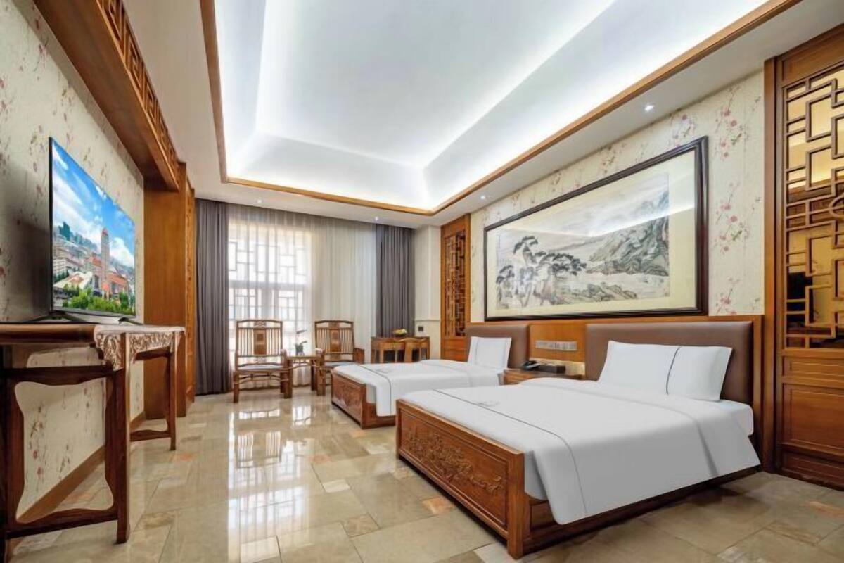 A hotel room with a bed, two bedside tables, a TV, a desk, and a chair.