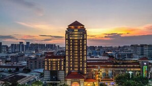 Un hotel de gran altura con una torre destacada, rodeado de otros edificios, al atardecer.