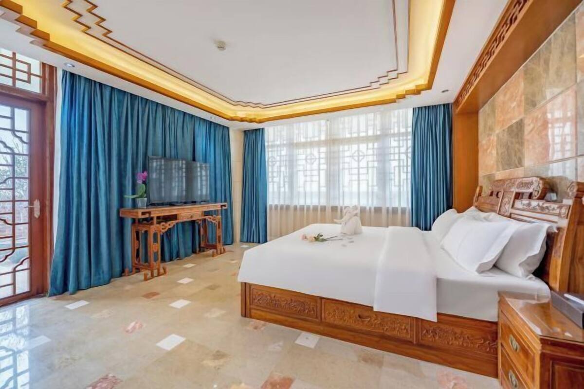 A hotel room with a large bed, a wooden desk, and a view through the window.