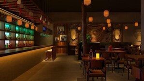 Un área de bar tenuemente iluminada con muebles de madera y faroles colgantes.