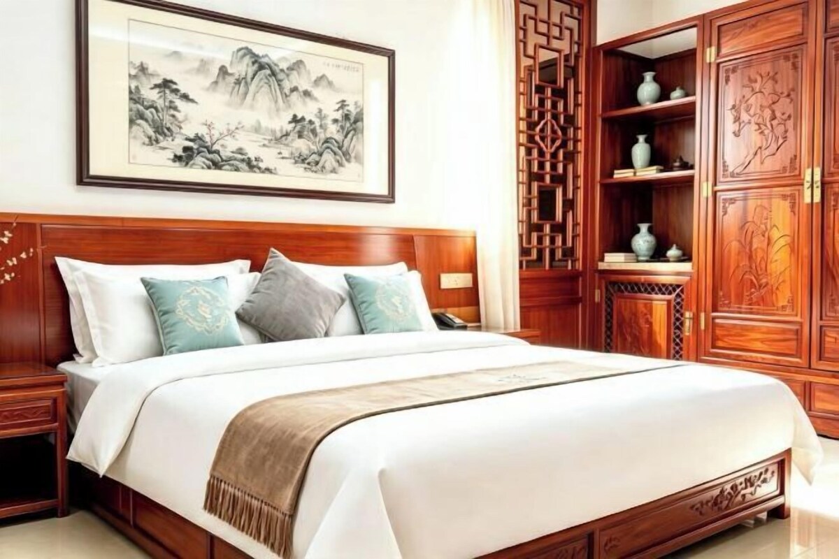 Habitación tradicional con cama, cabecero de madera y una obra de arte grande enmarcada en la pared.