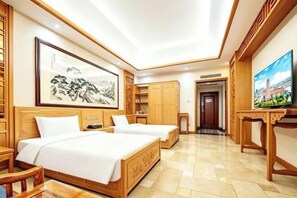 Habitación de hotel con dos camas, televisor, muebles de madera y obras de arte en las paredes.