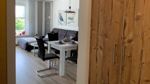 Een moderne woonkamer met een grijze bank, een eettafel met stoelen en kunst aan de muur.