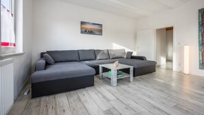 A modern living room with a grey sectional sofa, a small coffee table, and a painting on the wall. - Holiday Apartment "Bartölke" with Wi-Fi (Bockenem)