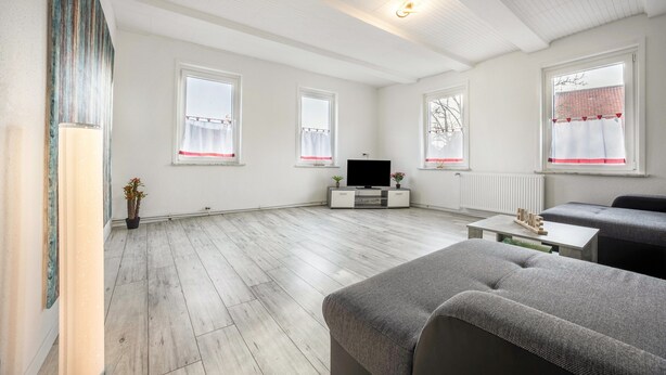 A spacious living room with a flat-screen TV, grey sofas, and a wooden coffee table. - Holiday Apartment "Bartölke" with Wi-Fi (Bockenem)