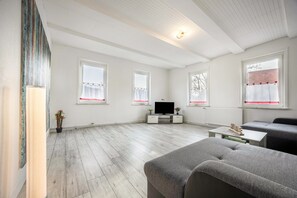 Un salón espacioso con televisor de pantalla plana, sofás grises y una mesa de centro de madera.