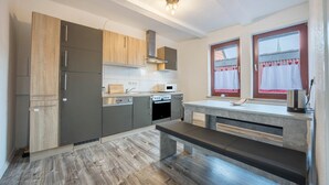 A modern kitchen with built-in appliances, a wooden bench, and a window with curtains. - Holiday Apartment "Bartölke" with Wi-Fi (Bockenem)