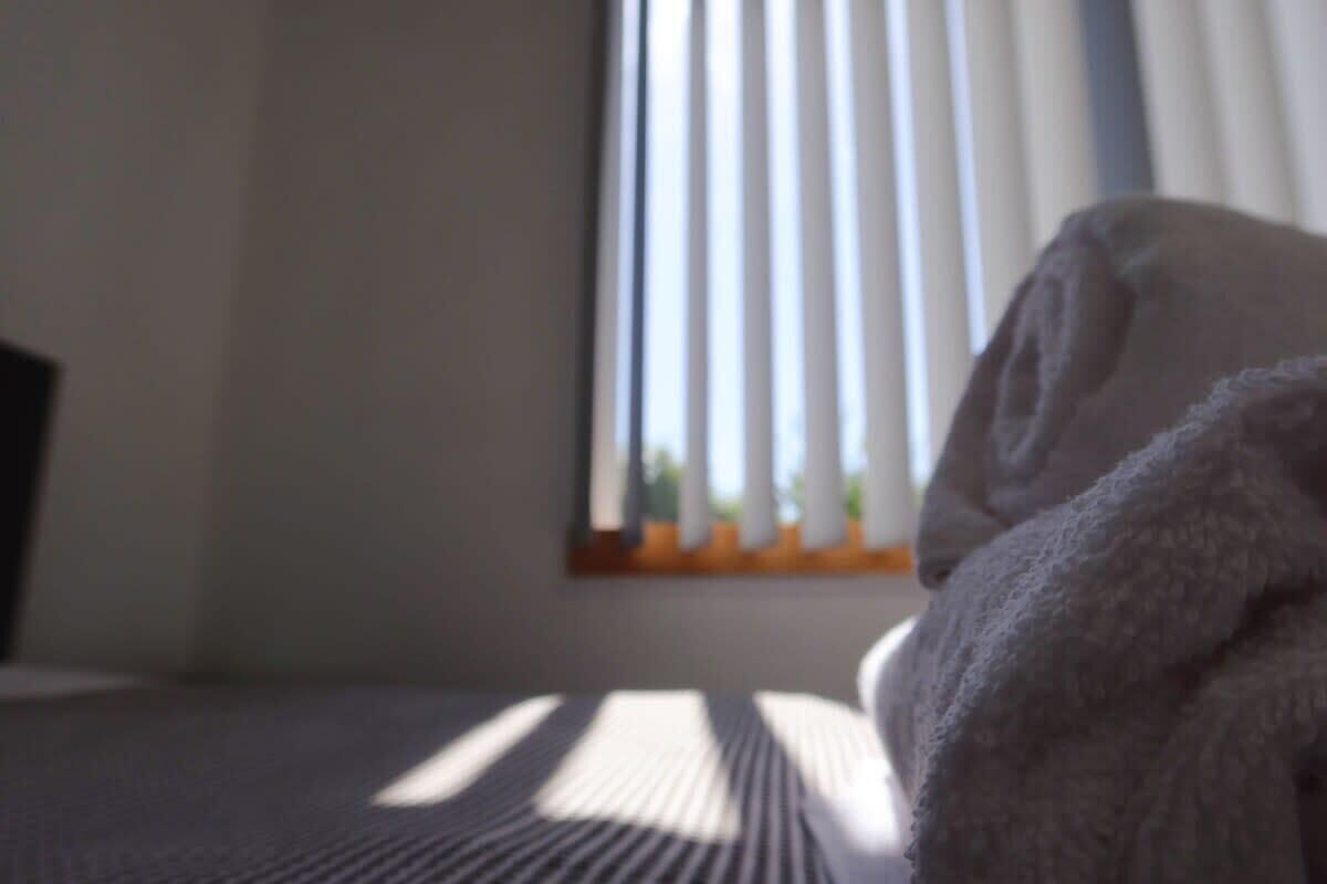Ein Bett mit einer gestreiften Tagesdecke und einem zusammengerollten Handtuch.