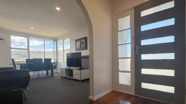 A modern room with a large window, a flat-screen TV, a desk, and a chair. - The Mountain Riveting House at Risdon vale (Risdon Vale)