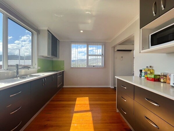 Une cuisine moderne dotée d’une grande fenêtre, d’un plancher en bois et d’appareils électroménagers intégrés.