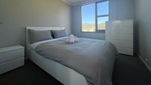 A bedroom with a bed, a dresser, and a window. - The Mountain Riveting House at Risdon vale (Risdon Vale)