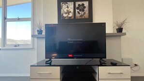 A modern office desk with a flat-screen TV, drawers, and a shelf with two framed artworks. - The Mountain Riveting House at Risdon vale (Risdon Vale)