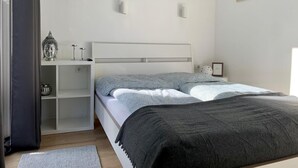 Ein Schlafzimmer mit Bett, Nachttischen, einem Regal mit Dekoration und Wandleuchten.