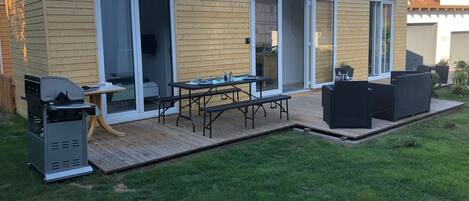 Une maison moderne dotée d’un patio, d’un barbecue et d’un coin repas.