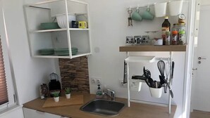 Eine kleine Küche mit Spüle, Arbeitsfläche und Regalen.