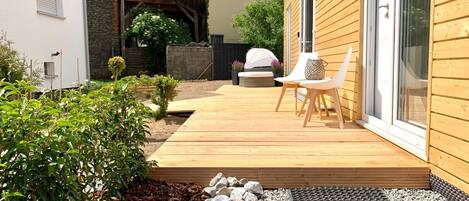 A wooden deck with outdoor seating, a stone pathway, and a small garden area.