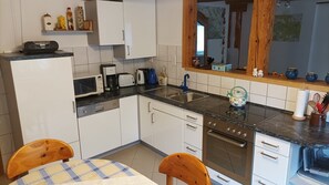 Una cucina con mobili bianchi, un forno a microonde, un tostapane, un lavandino e un fornello.