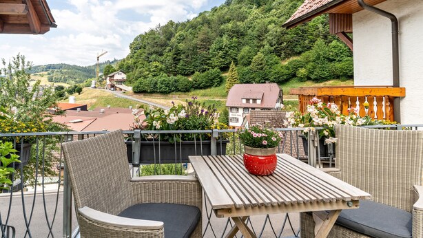 A balcony with wicker furniture, a table, and potted plants. - Apartment "Am Kapellenberg" with Mountain View, Shared Terrace & Wi-Fi (Bad Peterstal-Griesbach)