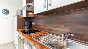 A modern kitchen with a wooden countertop, stainless steel sink, and a built-in range hood. - Apartment "Am Kapellenberg" with Mountain View, Shared Terrace & Wi-Fi (Bad Peterstal-Griesbach)