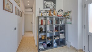 Un pasillo con una estantería, cuadros enmarcados y una puerta.