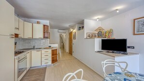 A compact kitchen with a gas stove, a sink, and a dining area with a table and chairs. - Astra 1 Veli Lošinj Harbour View, Veli Lošinj, Croatia (Veli Lošinj)