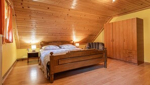 A bedroom with a wooden ceiling, a bed, a wardrobe, and a nightstand with a lamp. - Kunstek Farmhouse w/ Private Sauna, Rogatec, Slovenia (Rogatec)