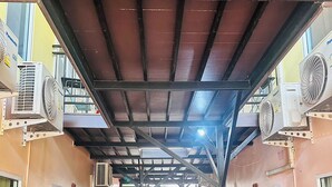 A covered outdoor area with a tiled floor, multiple air conditioning units, a fire extinguisher, and a staircase leading to an upper level. - Anyavee Chom By The Sea (Krabi)