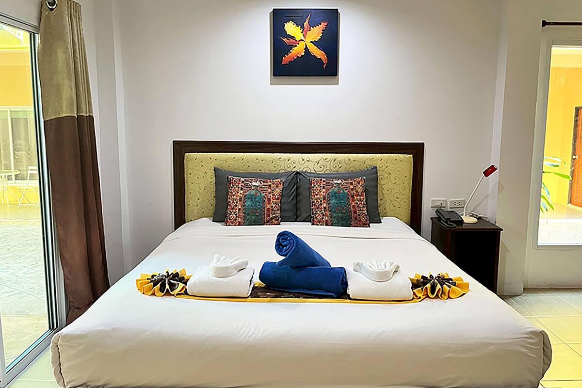 Una cama bien hecha con cabecera, almohadas y toallas.